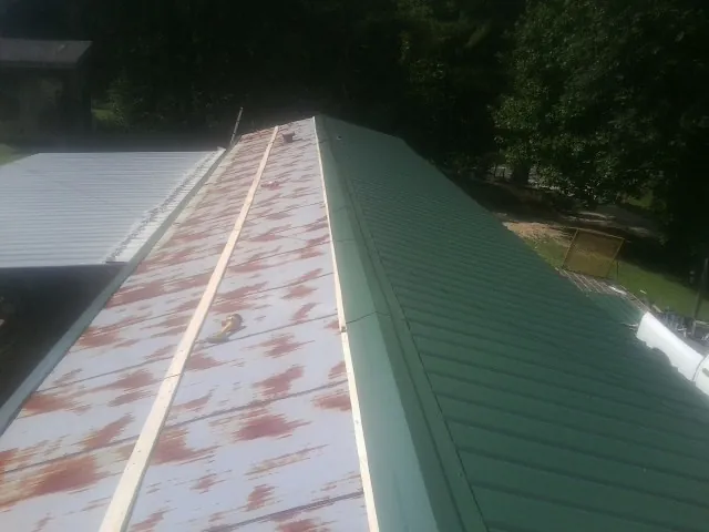 Old rusted panels beside newly installed green metal roofing — Wind Damage Roof Repair by Roofing Brothers in Union City