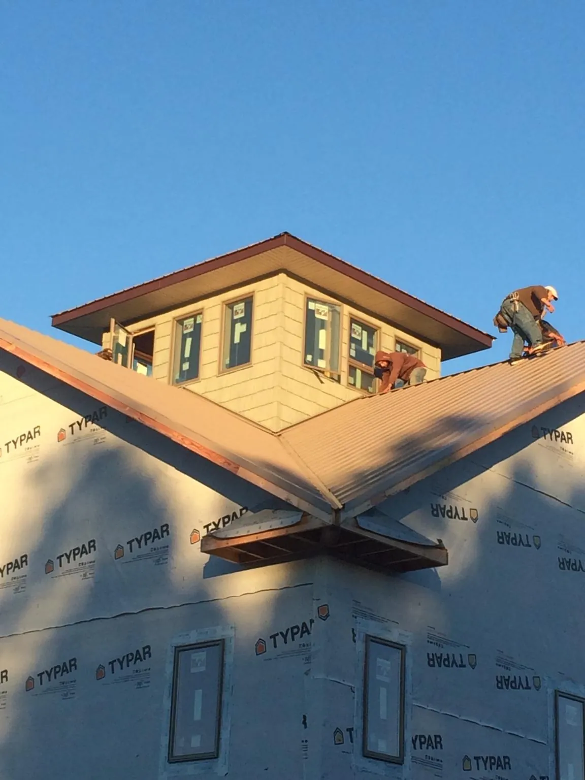 Roofers working around a rooftop cupola on a new metal roof at sunset — Roof Waterproofing in Union City by Roofing Brothers